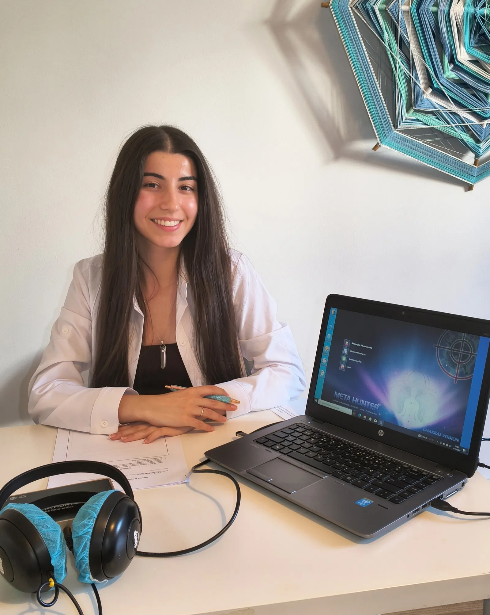Catarina na secretária da consulta, com o portátil da biorressonância e os auscultadores